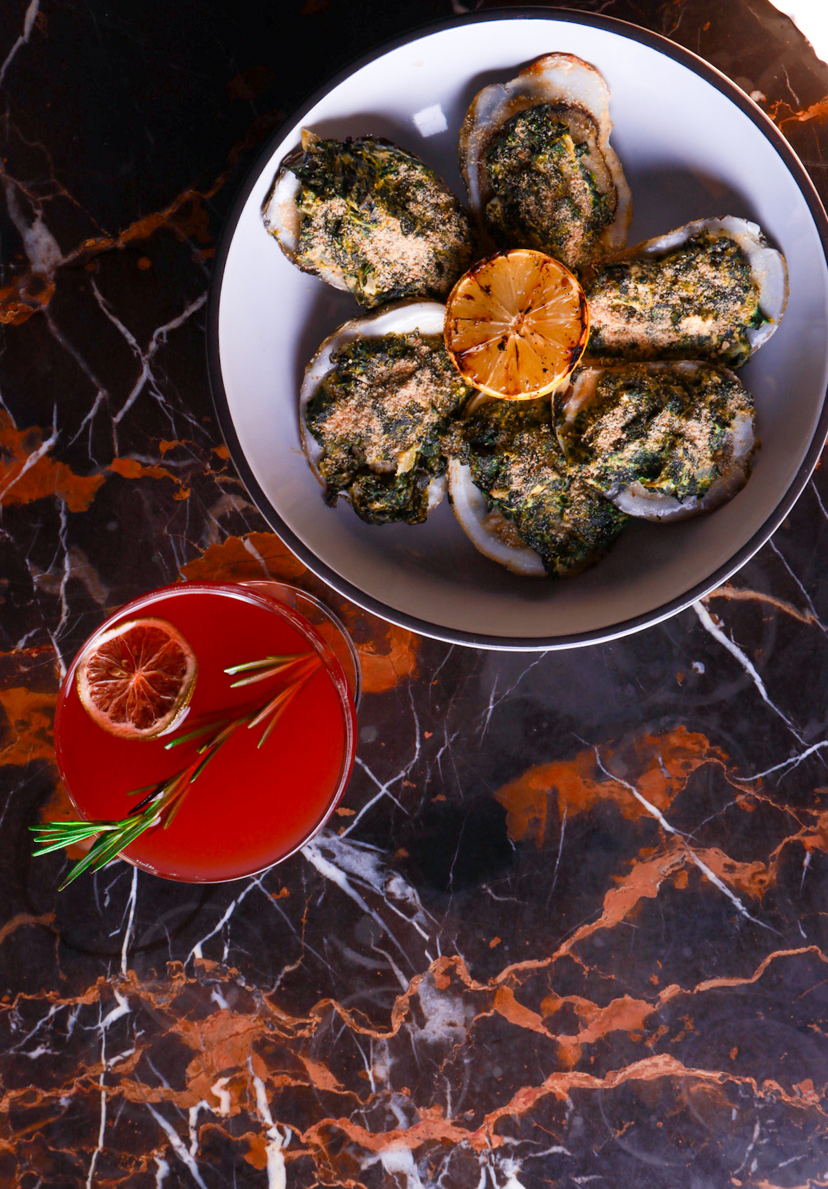 Shellfish course beside a cocktail on marble